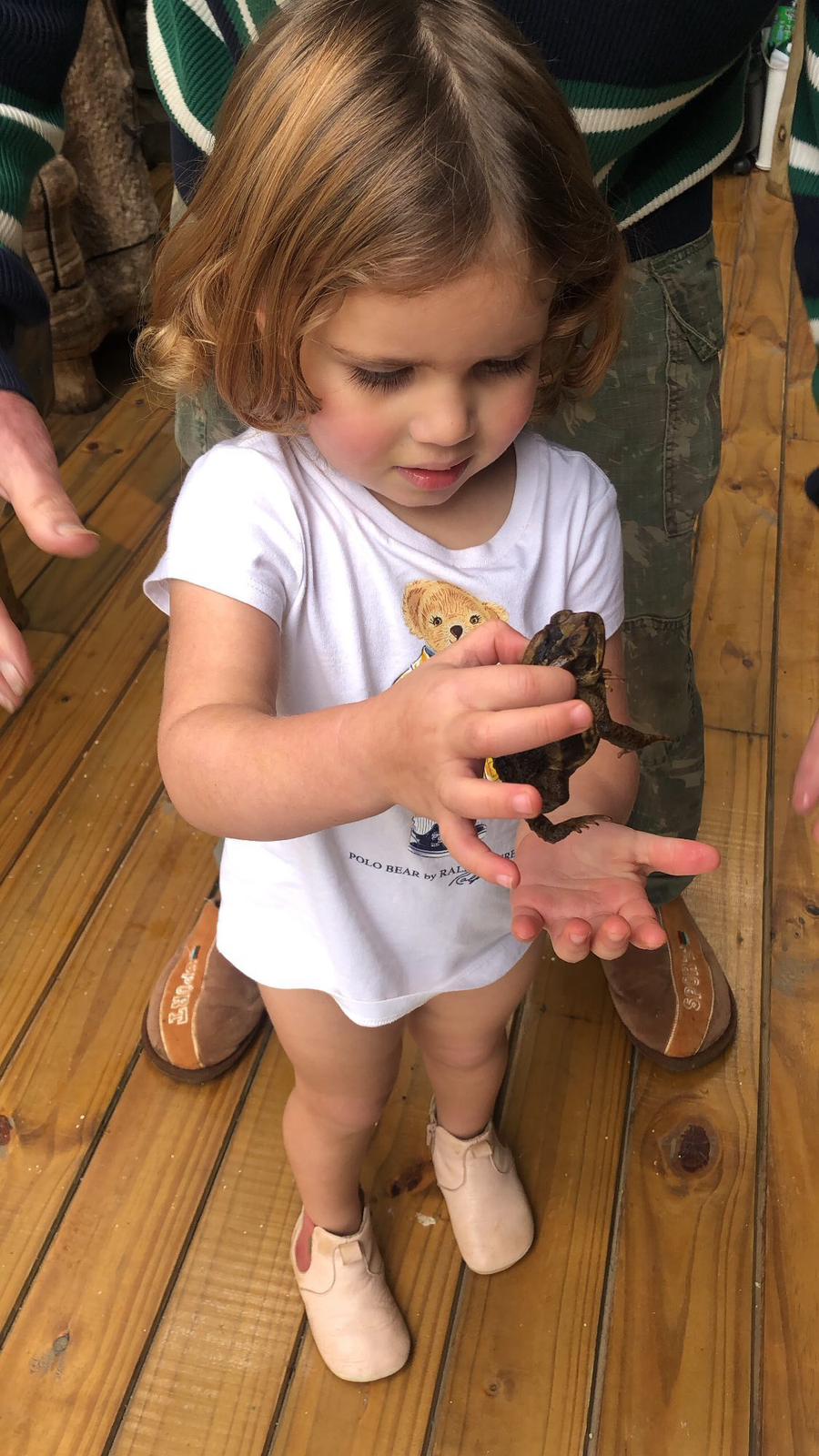 Trinity holding a frog on the porch