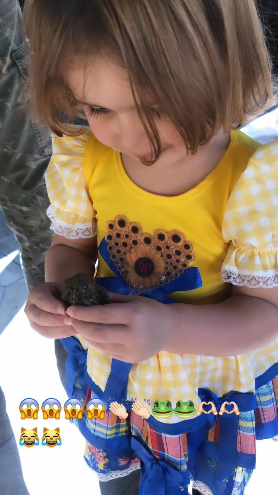 Trinity in costume holding frog with emojis